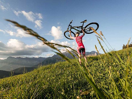 Frau triumphiert mit Mountainbike über Schultern die Watzmann-Hochkönig-Runde