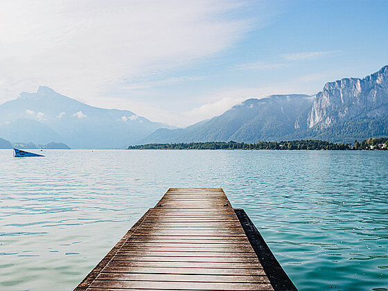 Ein Steg im Mondsee, im Hintergrund Bergpanorama