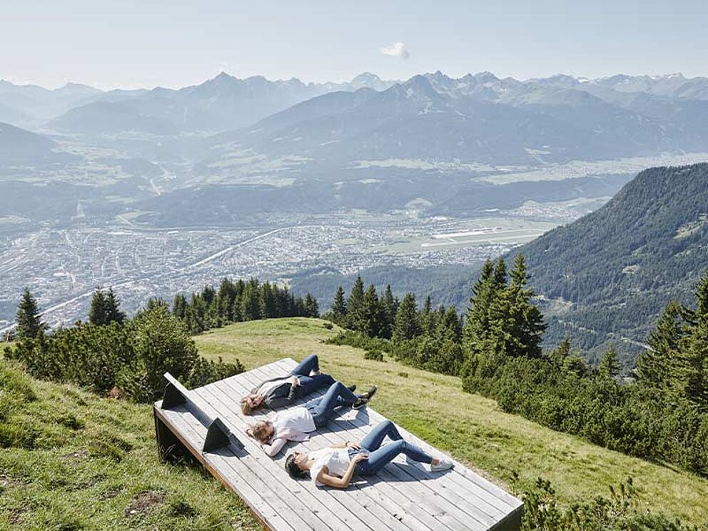 3 Personen auf einer Sonnenliege mit Panoramablick über Innsbruck