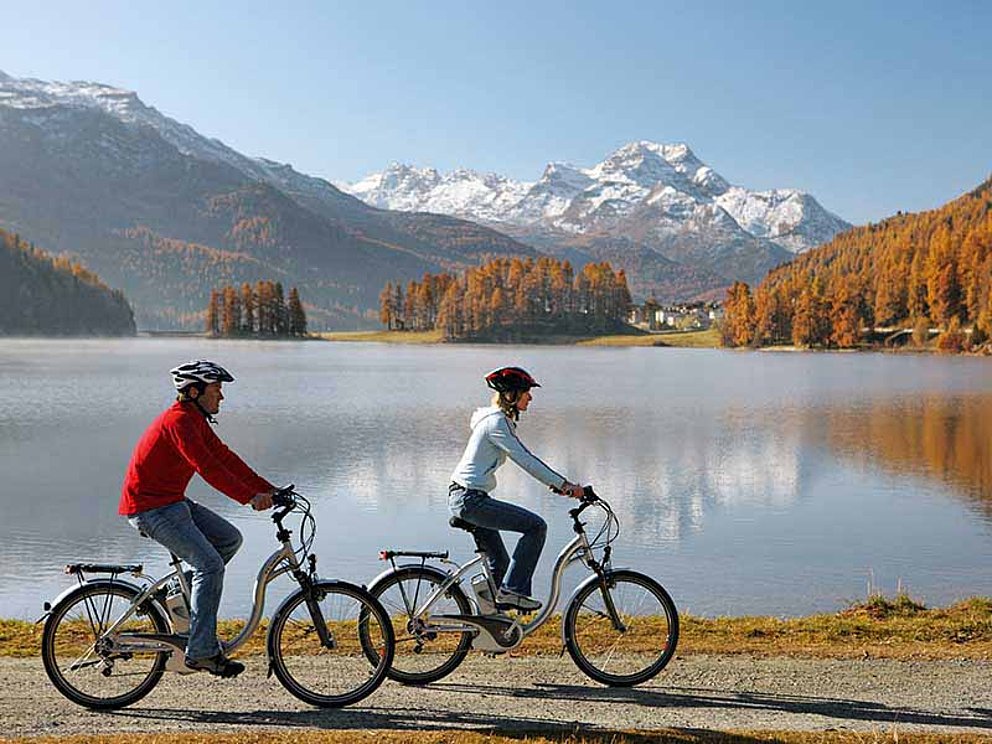 2 cyclists on electrically powered bikes on the lakeside of Lake Silverplanersee.