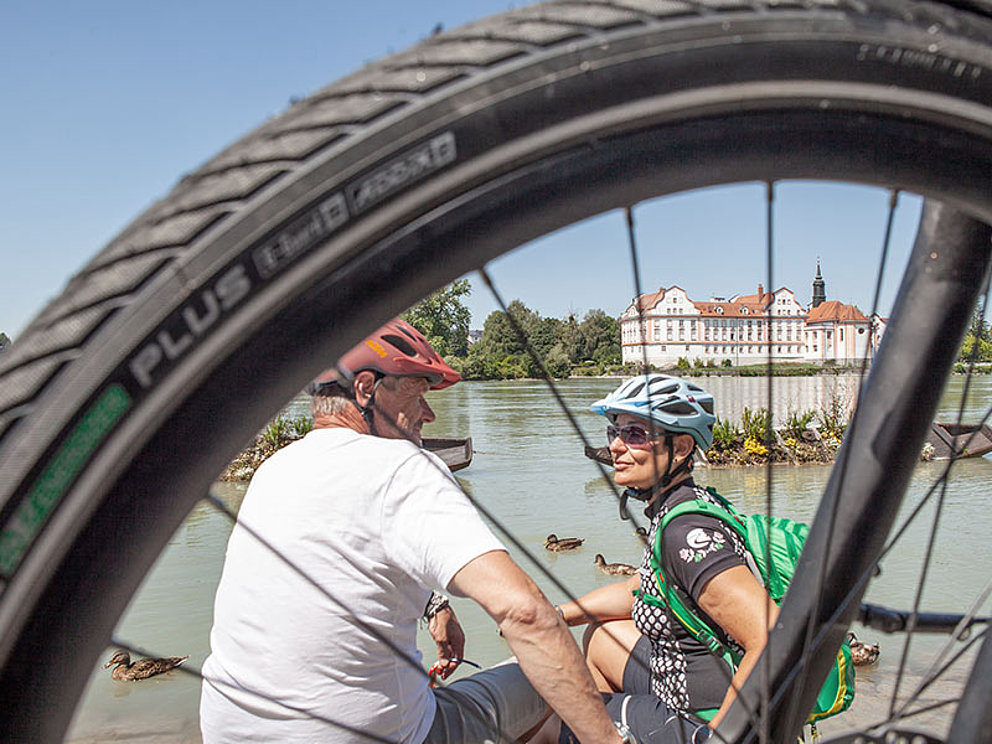 2 cyclists have a break on the riverbank in the cycling holidays in Austria