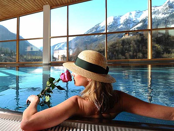 Eine Dame mit Rose und Strohhut relaxt im Pool des Sky Spa im Wellnesshotel Erzherzog Johann 