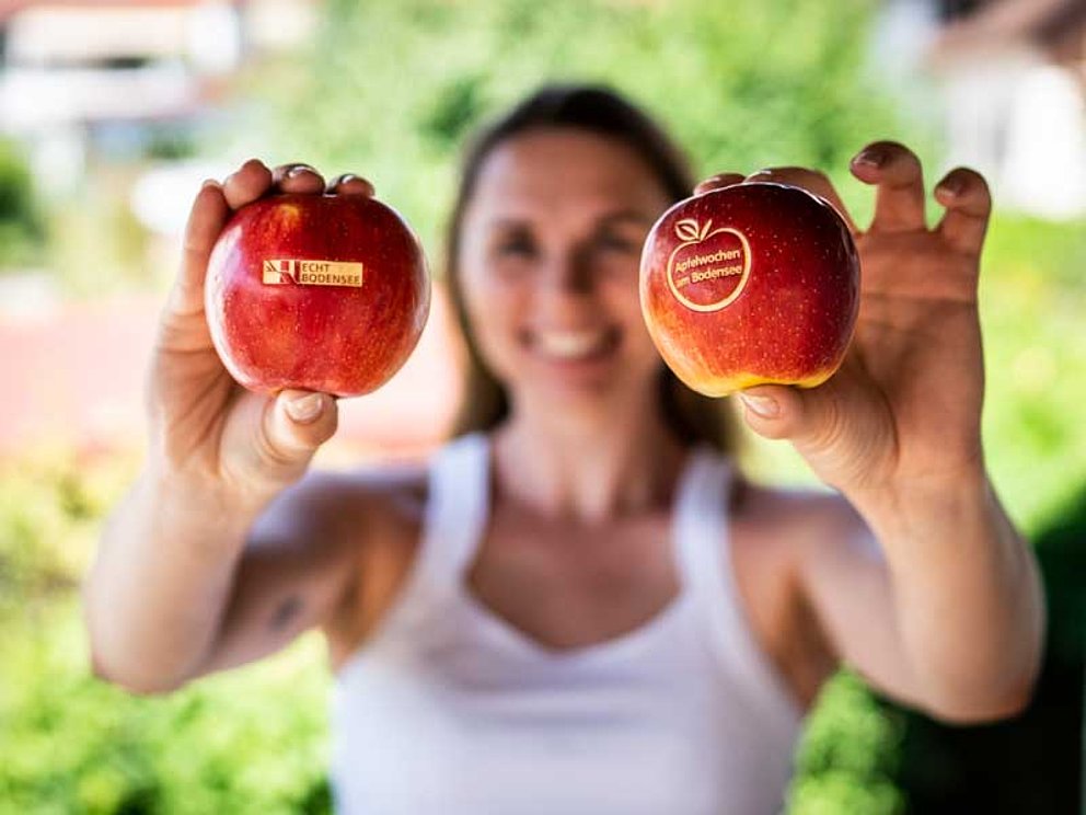 Frau hält 2 knackfrische Äpfel in die Kamera