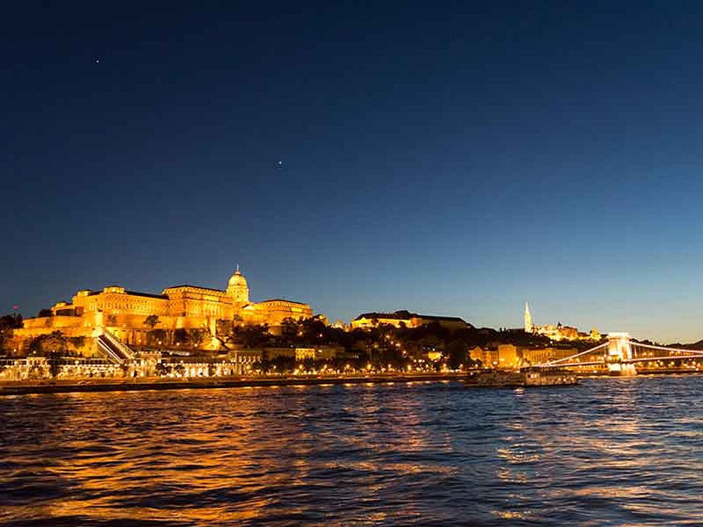 Blick bei Nacht über die Donau auf das beleuchtete Budapest mit Schloss und Kettenbrücke