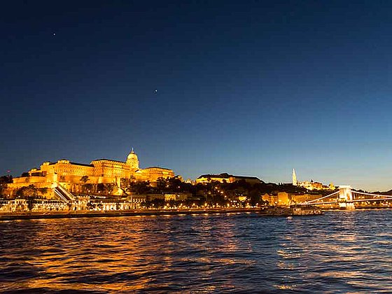 Blick bei Nacht über die Donau auf das beleuchtete Budapest mit Schloss und Kettenbrücke