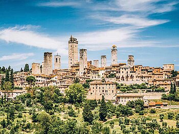 Panoramablick auf die mittelalterliche Stadt San Gimignano in der Toskana mit ihren charakteristischen hohen Geschlechtertürmen unter blauem Himmel.