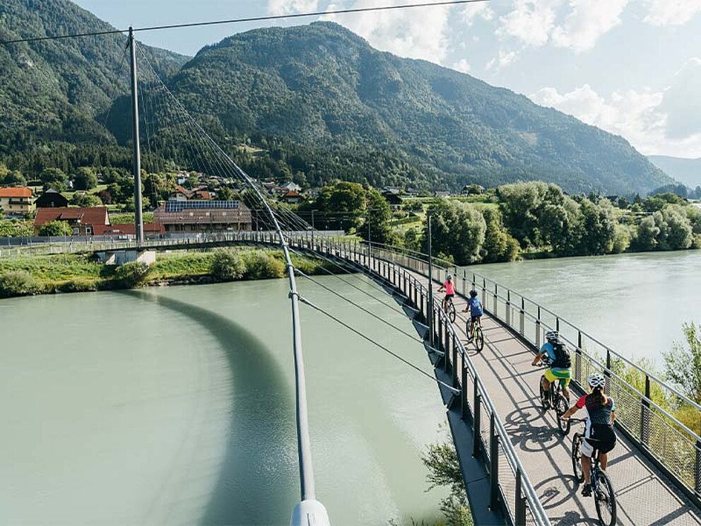 Radfahrer fahren über eine Drau-Brücke