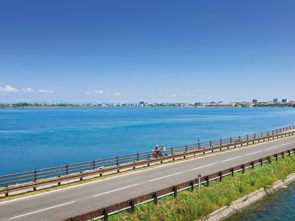 Luftaufnahme einer Brücke vor Grado mit Radfahrern
