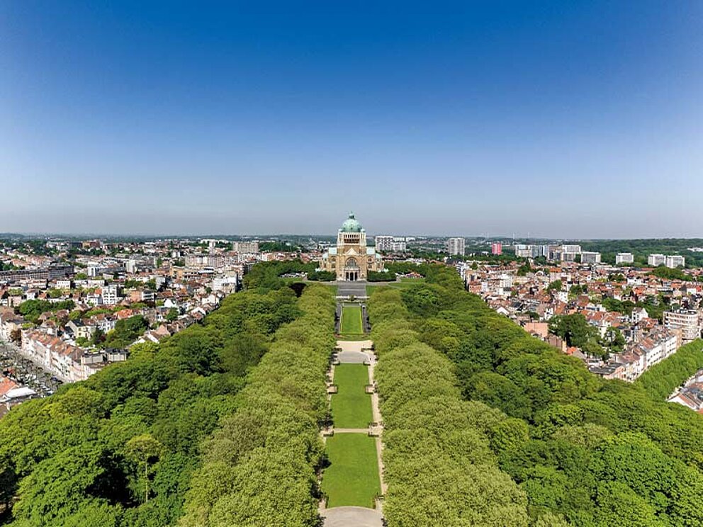 Luftaufnahme des Parc du Cinquantenaire in Brüssel, Belgien, mit symmetrischer Parkanlage und dem Triumphbogen im Hintergrund.