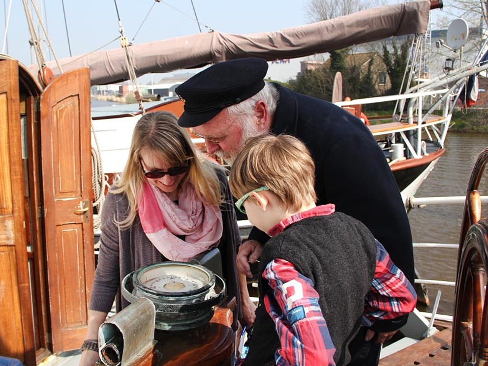 Kapitän zeigt den Gästen den Kompass an Board der Elizabeth im Ijsselmeer