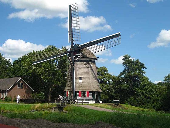 Eine reetgedeckte Windmühle in Holland mit 4 Flügeln.