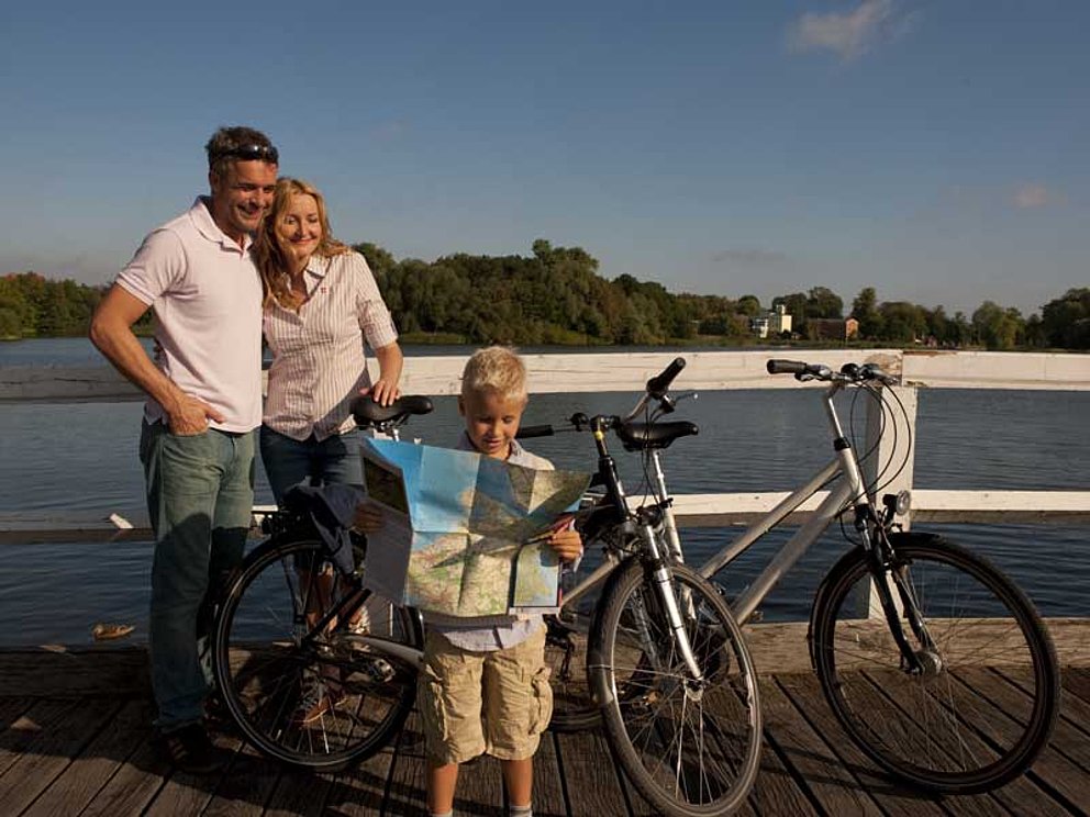 Eltern mit Knirps und Fahrrädern auf einer Brücke über der Ostsee