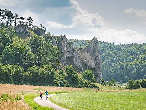 2 Radfahrer am Radweg, im Hintergrund schroffe Felsen