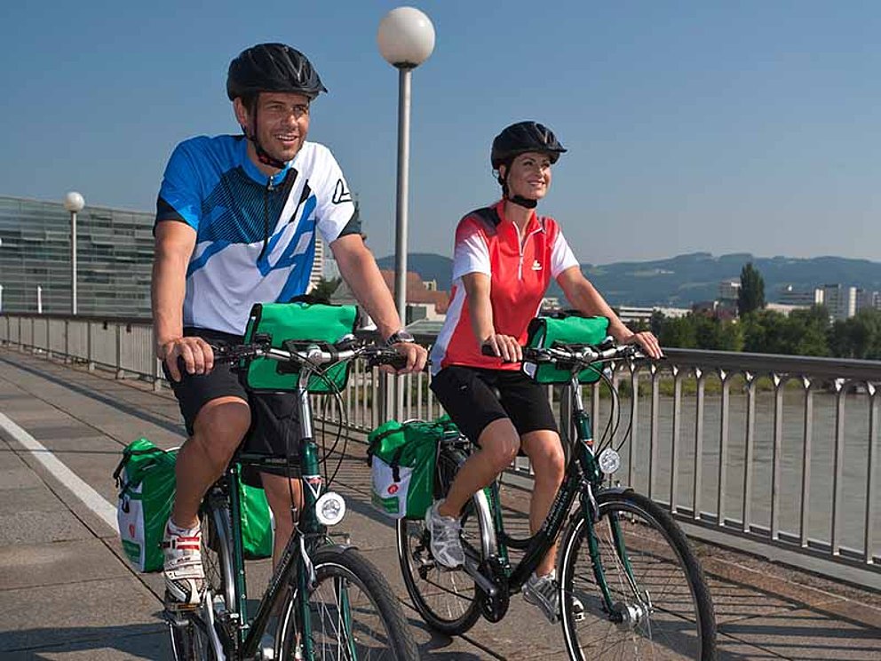 Zwei Radfahrer fahren über die Nibelungenbrücke in Linz