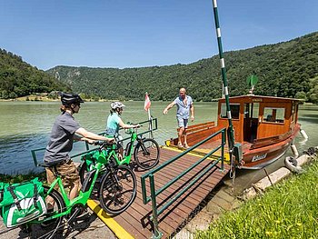 cyclists enter the ferry at the Danube River