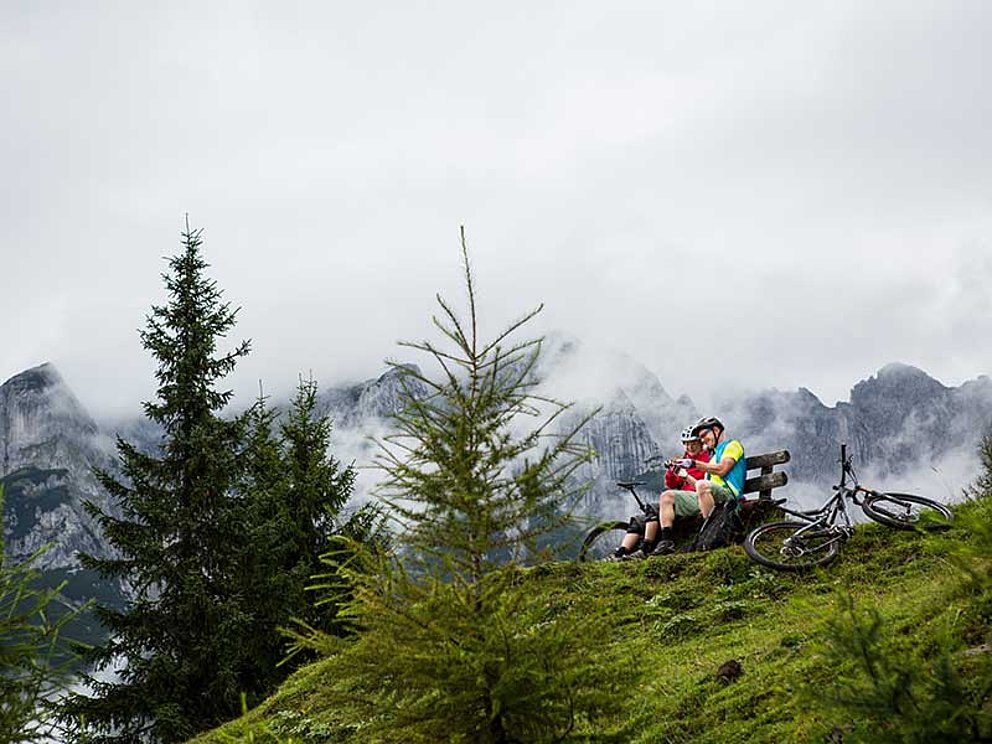 Mountainbiker-Paar machen Pause auf einer Bank auf der Alm