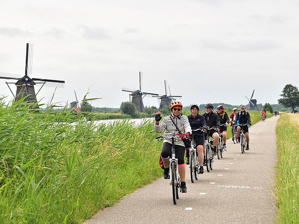 Radfahrer am asphaltierten Radweg, im Hintergrund 5 Windmühlen