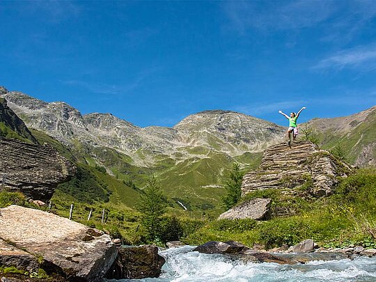 eine Dame steht auf einem Felsen, im Hintergrund Bergpanorma