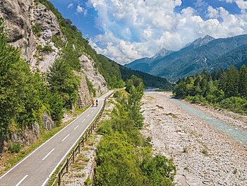Kanaltal mit Fluss, einem Radweg und Bergpanorama