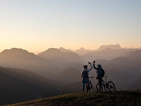 2 Mountainbiker in der Abenddämmerung vor herrlicher Bergkulisse