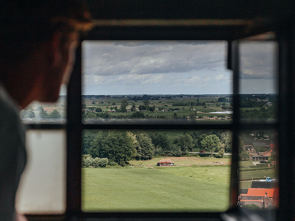 ein Mann schaut aus dem Fenster auf die umliegende flache Landschaft