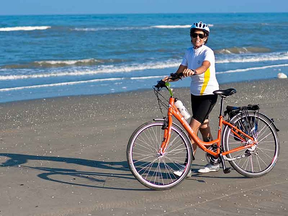 Frau mit Fahrrad am Strand in der Nähe von Venedig