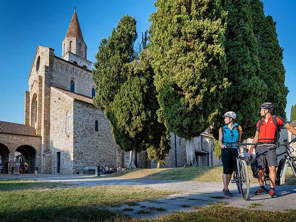 2 Personen mit Rad vor einer italienischen Kirche