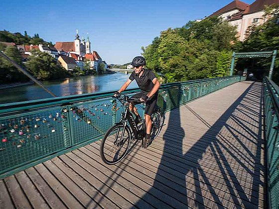 cyclist crosses a wooden bridge over Steyr River 
