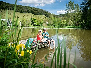 2 cyclists sit on a landing stage at River Altmühl, 