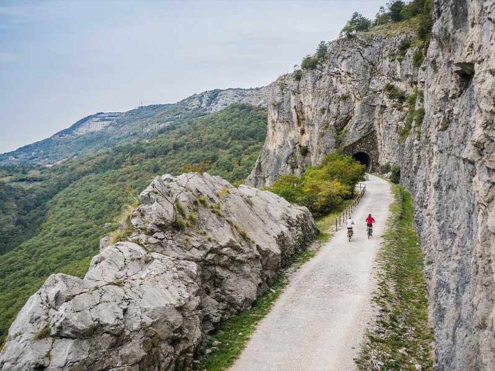 2 Biker auf eiem Schotterweg umgeben von Felsen.