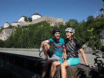 ein Paar auf einer Steinmauer, im Hintergrund die Festung Kufstein