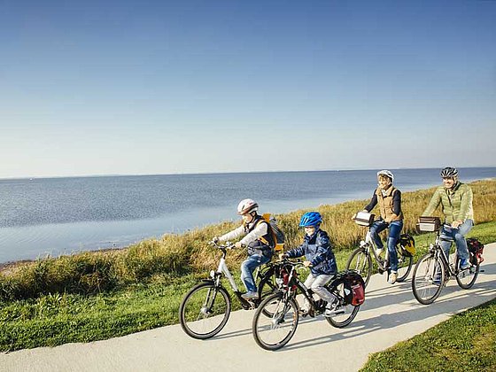 Eltern und zwei Kinder radeln an der Ostsee auf Rügen