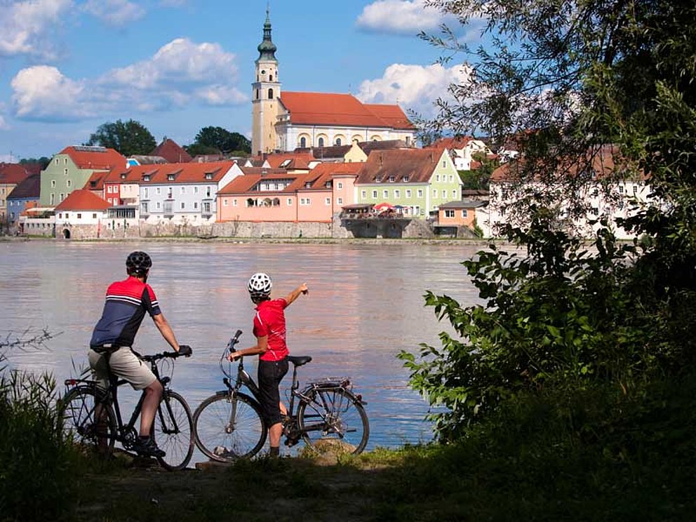 Radfahrer blicken von anderer Donauseite auf Schärding