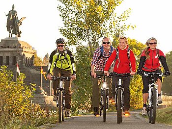 Radfahrergruppe in Koblenz vorbei am Kaiser-Wilhelm-Denkmal