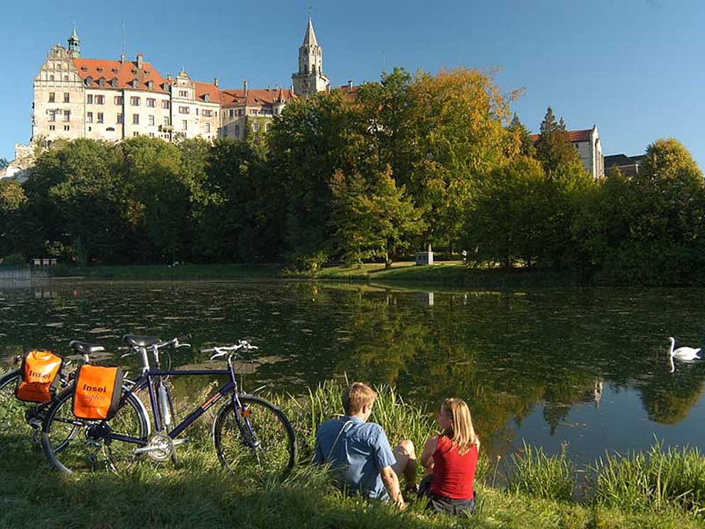 Radfahrer blicken von Donau-Ufer auf das Schloss Sigmaringen