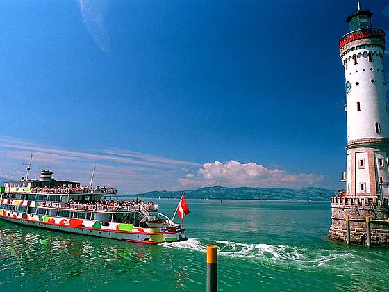 auslaufendes Schiff mit Leuchtturm am Bodensee in Lindau in Deutschland