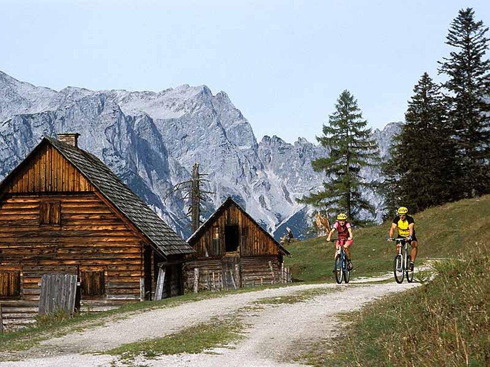 zwei Biker unterwegs im Nationalpark Gesäuse vorbei an Almhütten