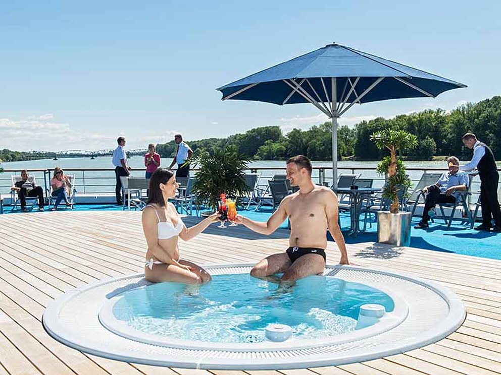 Paar mit Cocktails im Außen-Whirlpool an Deck der MS Primadonna