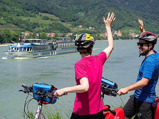 2 Radfahrer winken dem Schiff MS Swiss Crown zu