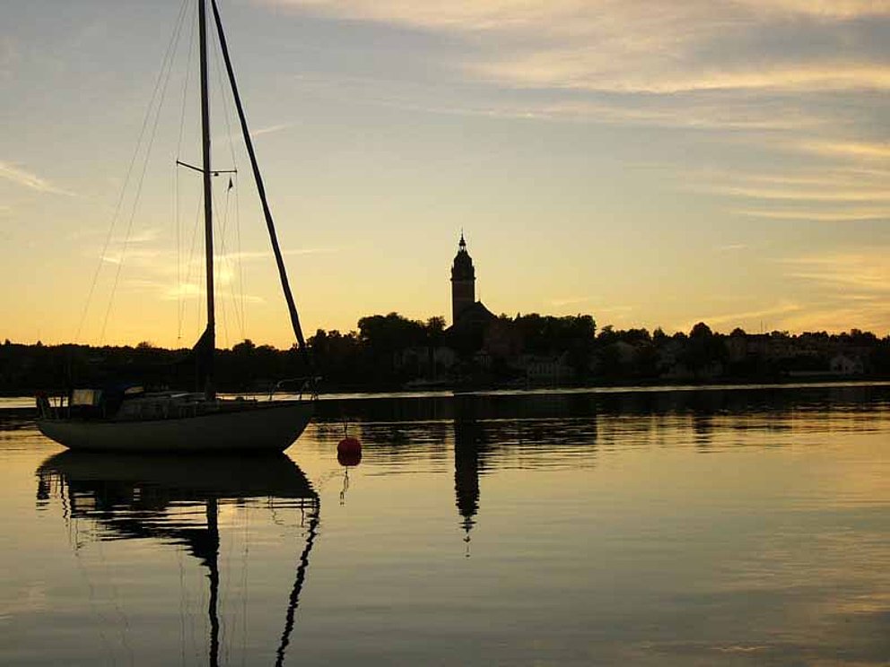 Kleines Segelschiff im Hafen von Strängnäs bei untergehender Sonne.