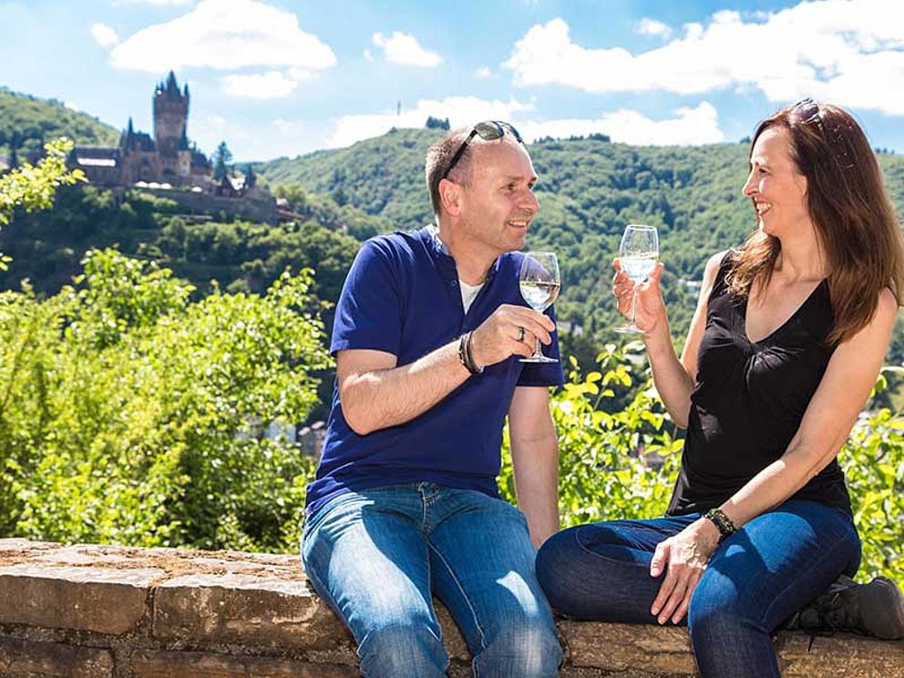 Paar mit Weingläsern vor Weinberg in Cochem in Deutschland