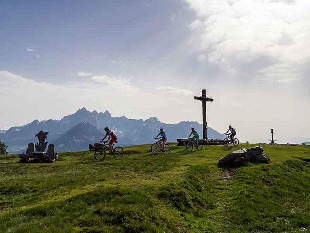 4 Mountainbiker unterwegs am Gipfelkreuz auf der Dachsteinrunde