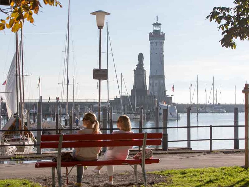 2 people on a bench admiring the harbour of Lindau