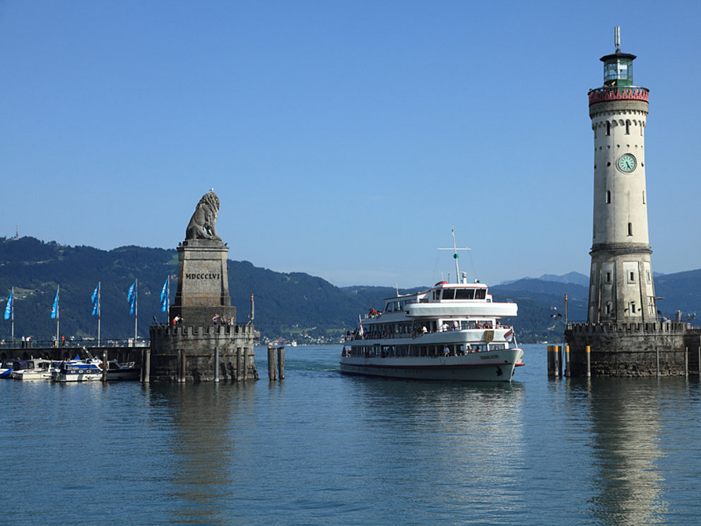 excursion boat leaves the harbour between statue and lighthouse