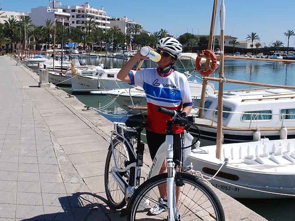 Radfahrerin trinkt in einer Bucht in Mallorca