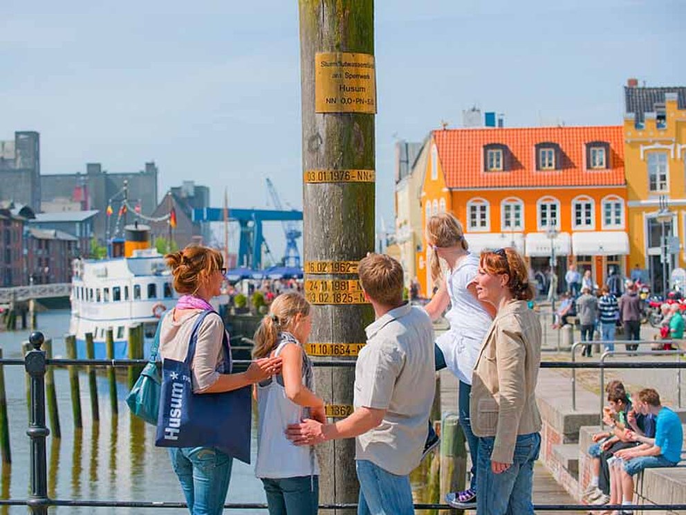 Menschengruppe an einer Säule im Hafen in Husum an der Nordsee