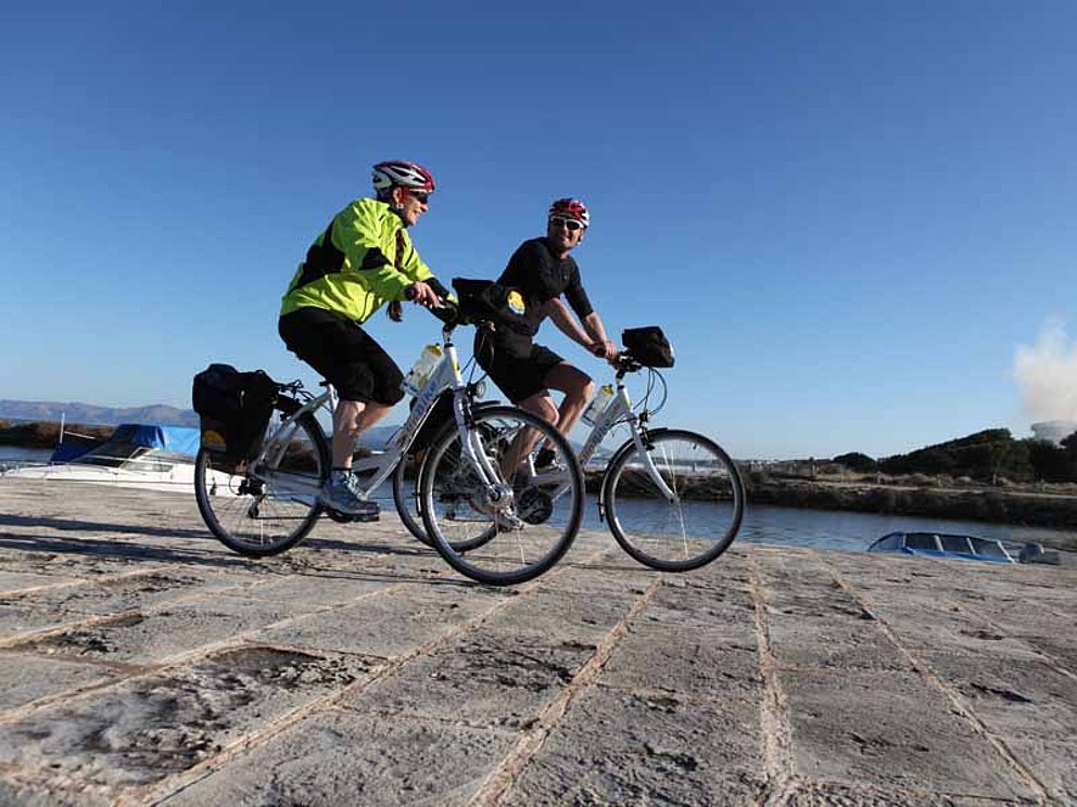 Radfahrer auf Kopfsteinpflaster in einem Yachthafen auf Mallorca.