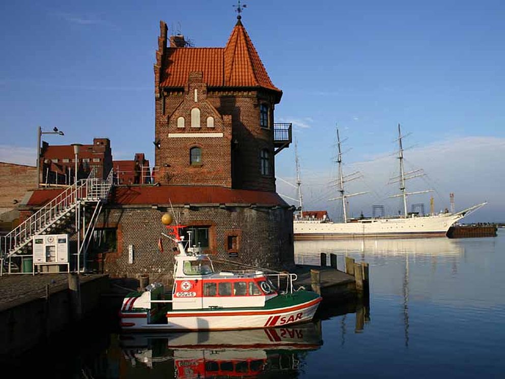 Blick auf Gorch Fock und Lotsenstation in Stralsund mit vorbeifahrendem Boot