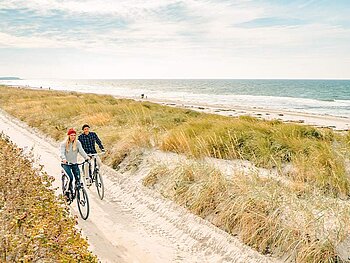 2 Radfahrer am sandigen Radweg an der Ostseeküste
