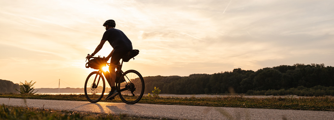 ein Radfahrer bei Sonnenuntergang am Donauufer